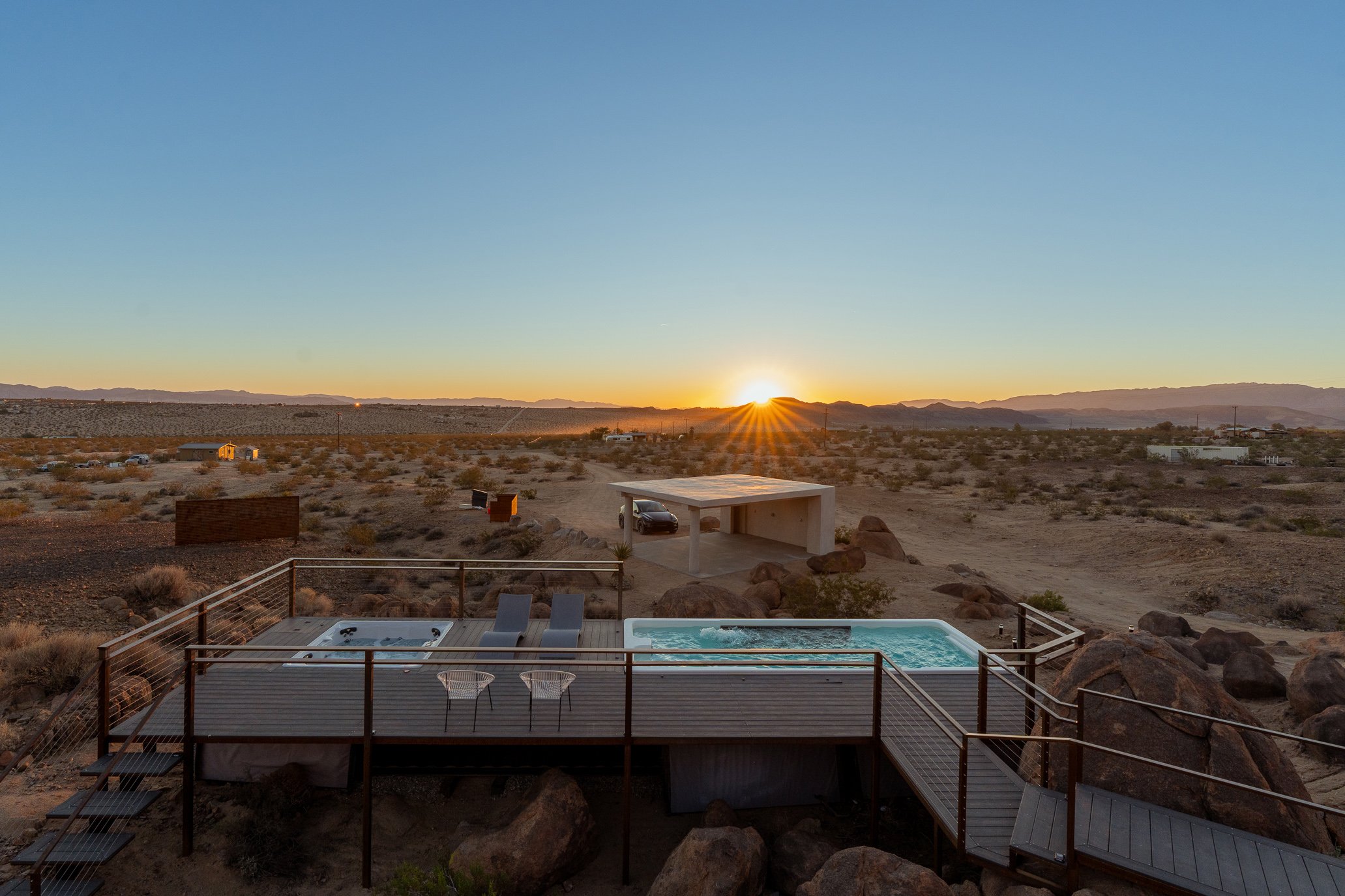 Container pool and hot tub on an elevated desert deck at sunrise
