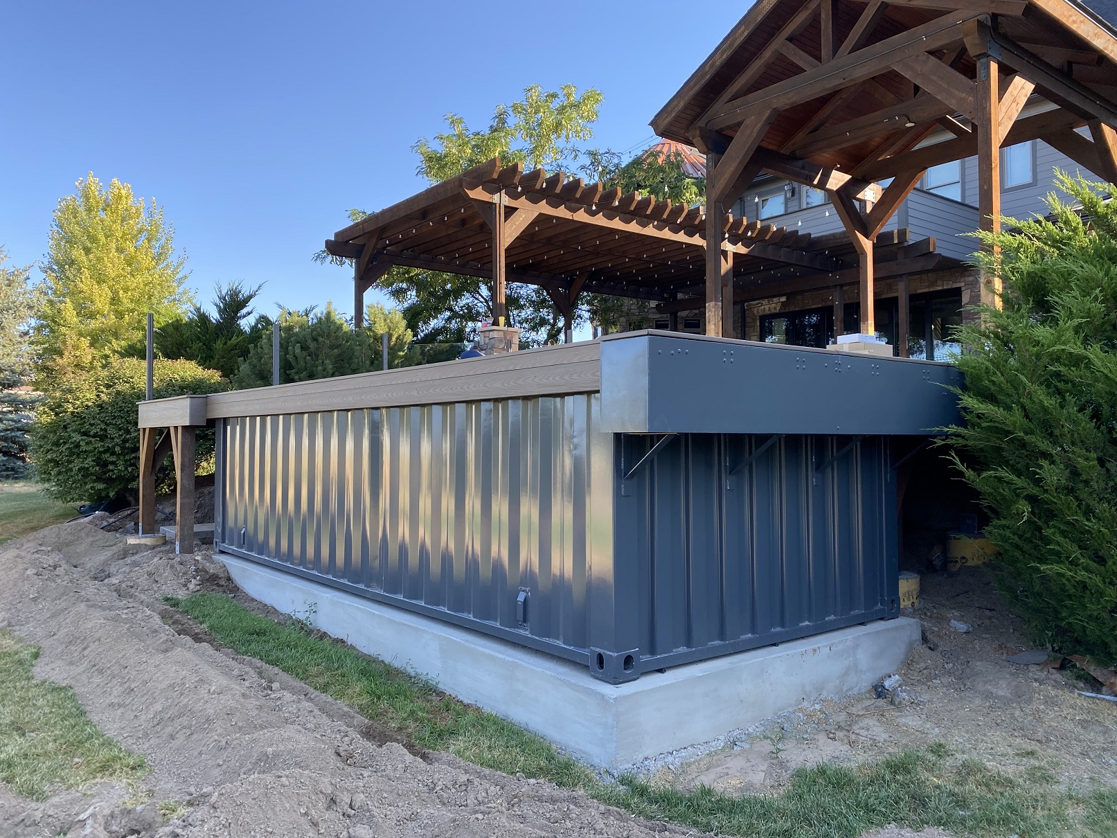 Container pool set on a concrete base under construction with pergola and landscaping