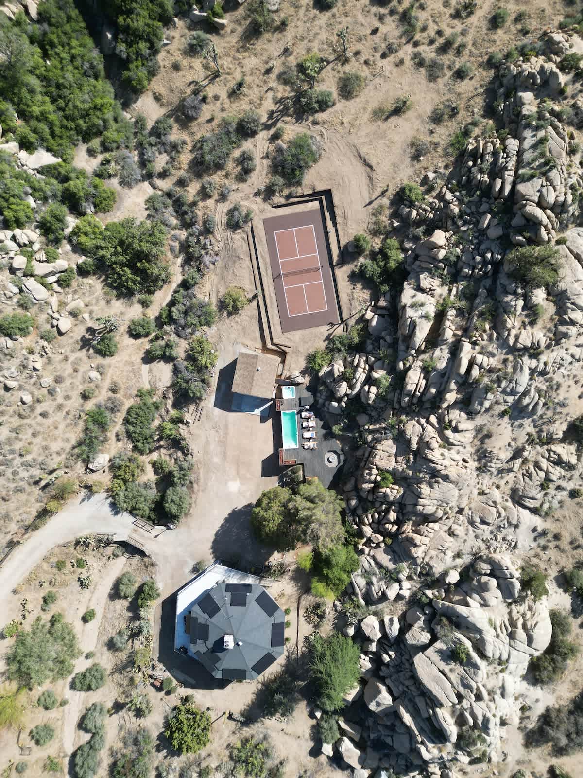 Aerial of Joshua Tree desert property with container pool, sport court, and pool house