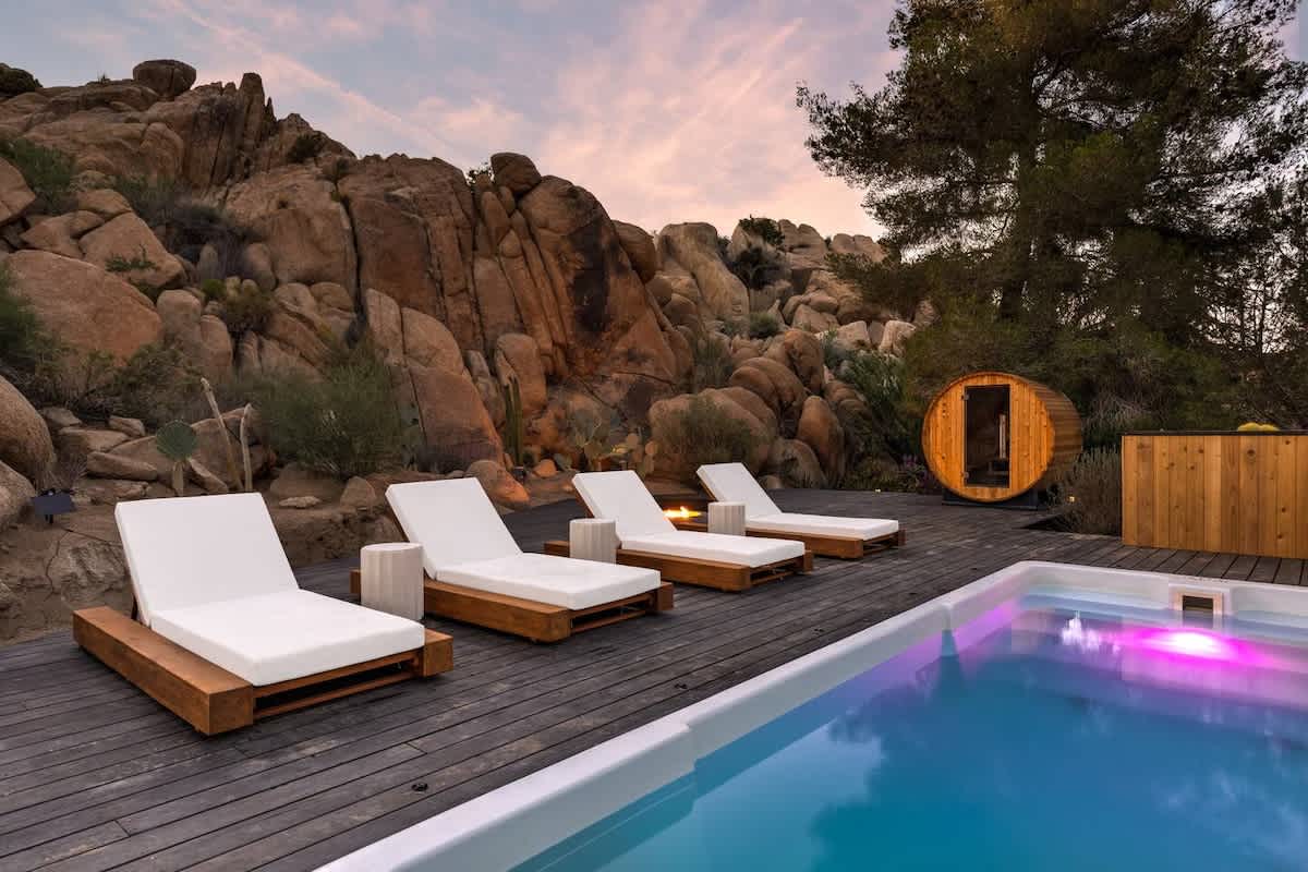 White fiberglass container pool lit magenta by standard ColorLogic LED lighting at dusk in Joshua Tree, California
