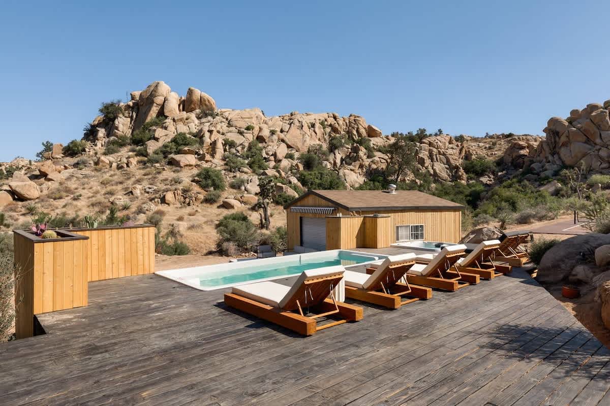 Wide view of a container pool and deck against a boulder hillside in Joshua Tree, California