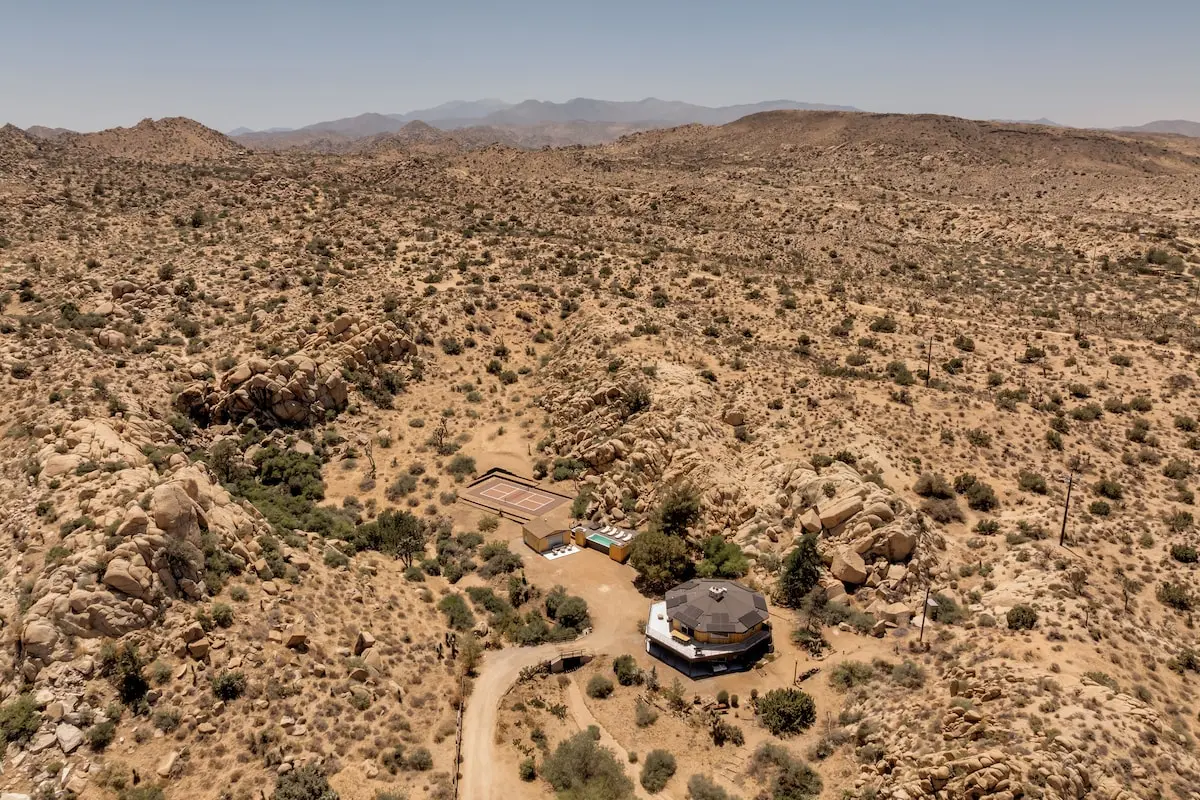 Wide aerial of desert landscape surrounding a container pool property near Joshua Tree, California