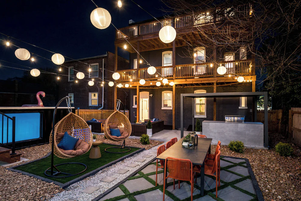 Backyard at night with string lights, seating, and a container pool with a lit acrylic viewing window in St. Louis