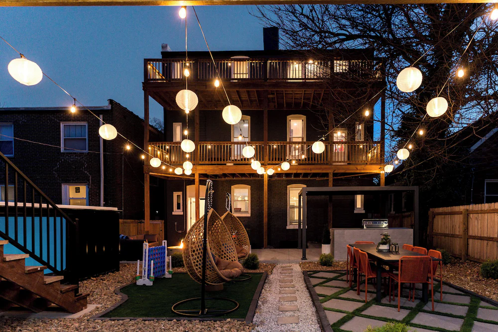 Container pool and backyard lit at night with string lights beside a St. Louis rental home